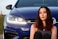 a woman sitting in front of a blue car
