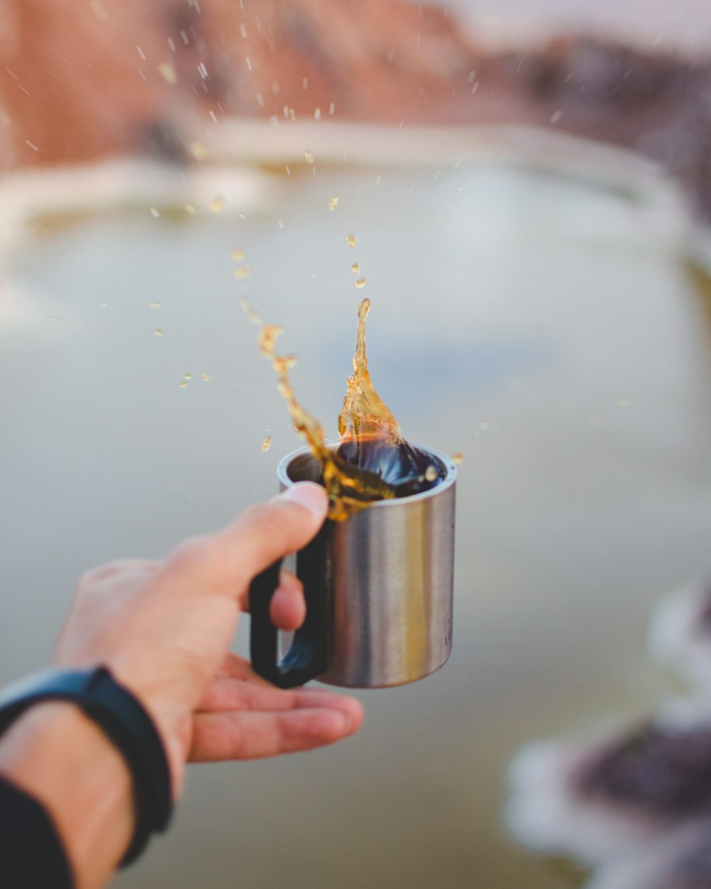 person holding sivler mug