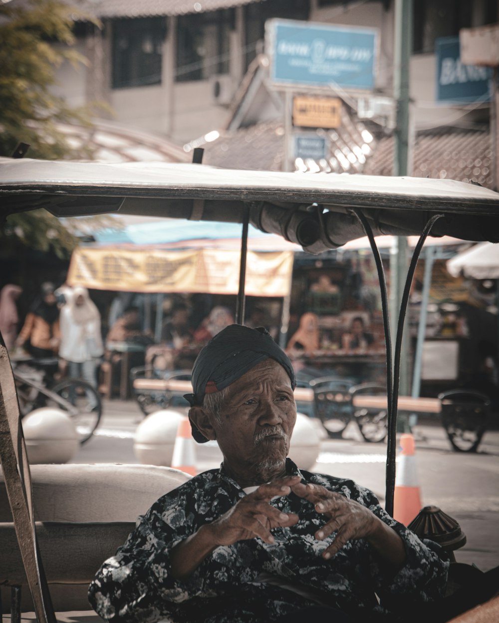 old man wearing black and white floral collared button-up long-sleeved shirt sitting inside vehicle