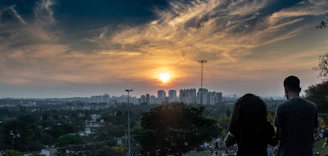 A warm sunset over Dziriya’s city skyline with people enjoying a park gathering.