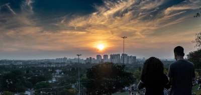 A warm sunset over Dziriya’s city skyline with people enjoying a park gathering.