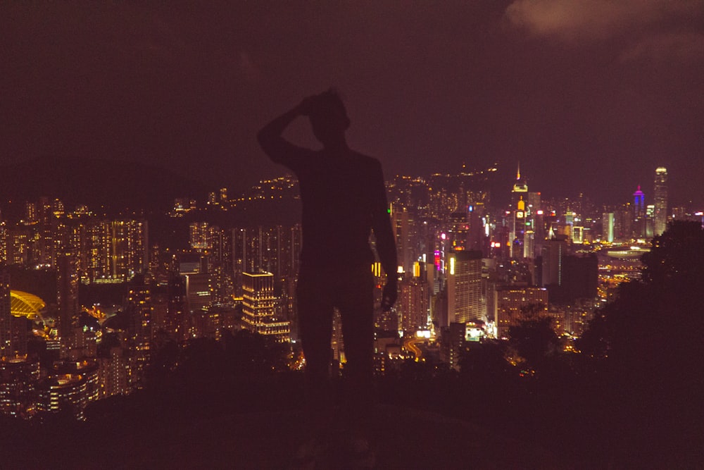 silhouette photography of man overlooking urban city