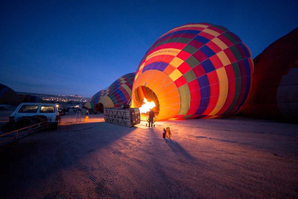 person standing near multicolored hot air balloon during night time