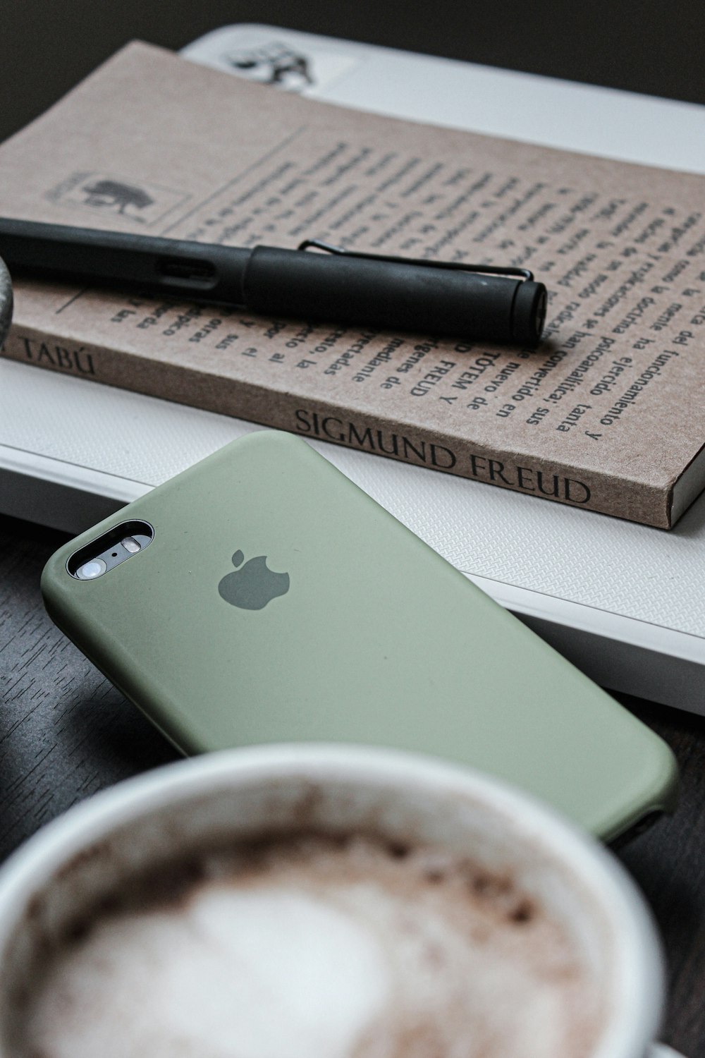 black pen and iPhone with olive-green case