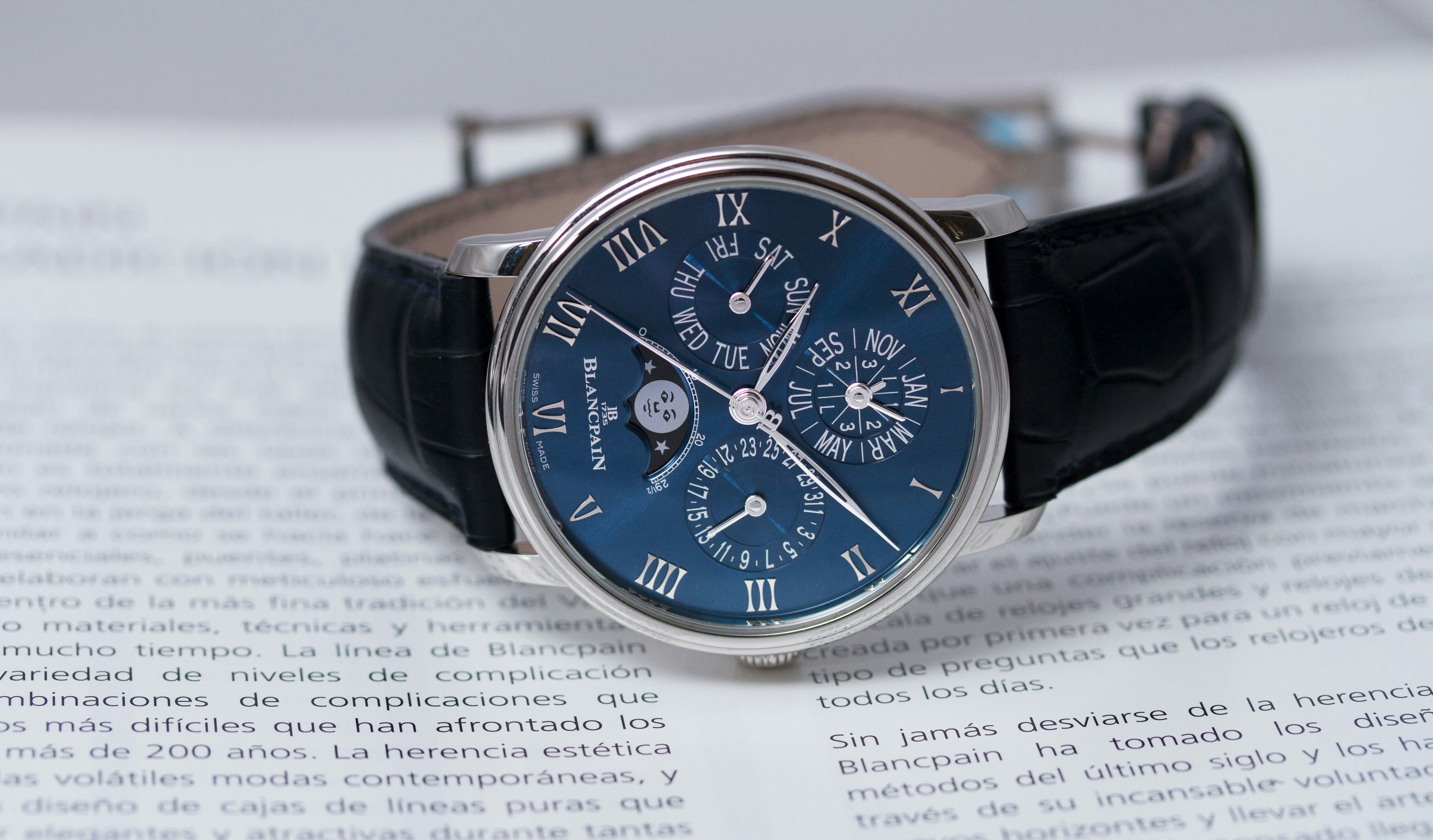 Un reloj Blancpain de calendario perpetuo con caja plateada y correa de piel negra.