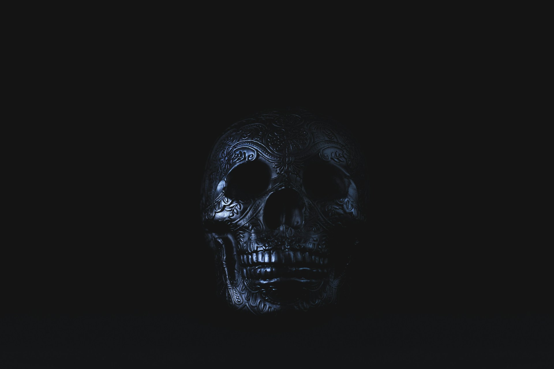 silver-colored skull accessory on black surface