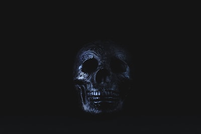 silver-colored skull accessory on black surface skull teams background