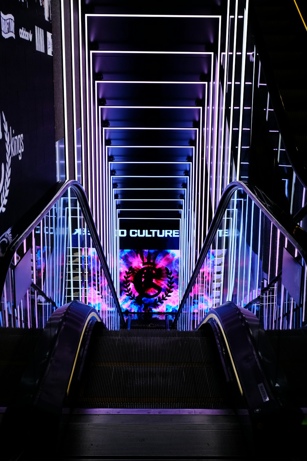 an escalator in a building with neon lights