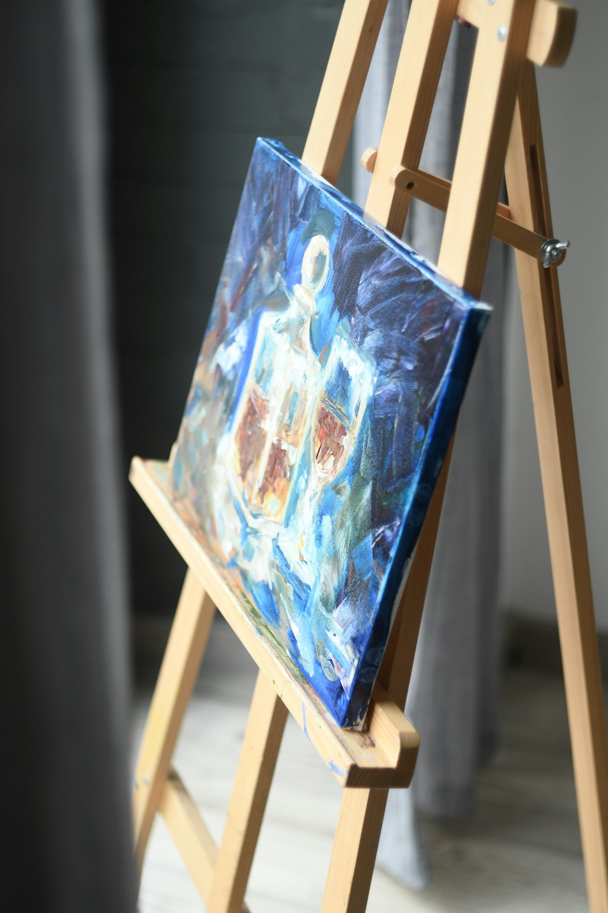 A blue and white oil painting resting on a wooden easel