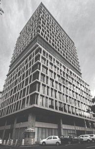 Modern commercial building with large windows and a parking lot in front.