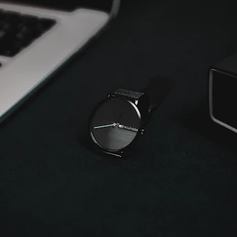 A sleek black and white minimalist luxury watch on a metallic surface.