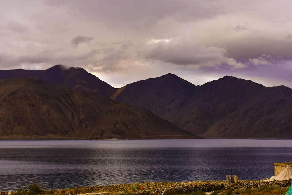 green mountain and calm body of water