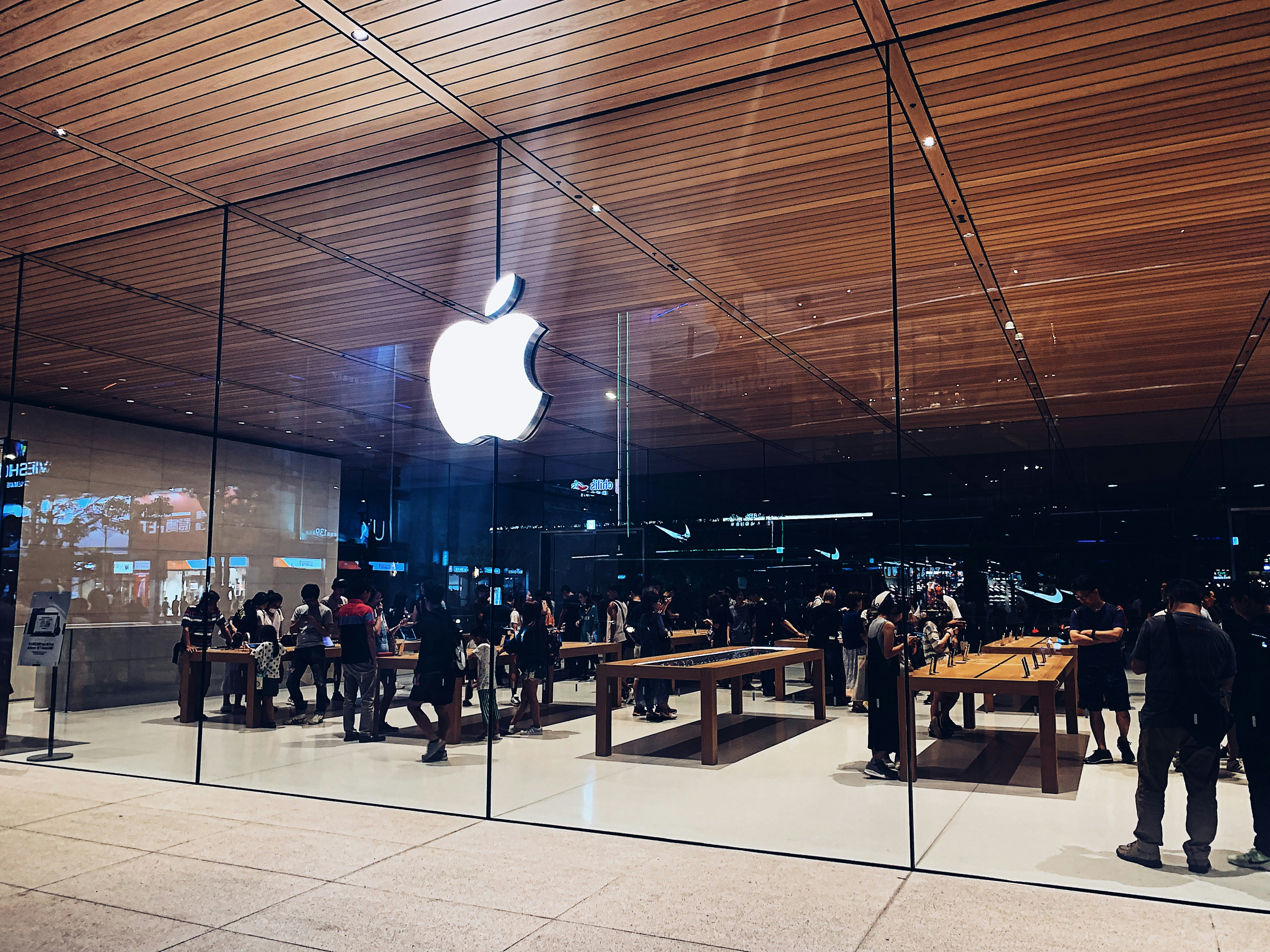 Apple store with glowing logo and people browsing products