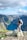 man standing on rock looking towards lake