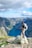 man standing on rock looking towards lake