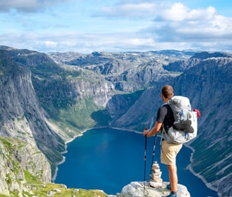 man standing on rock looking towards lake