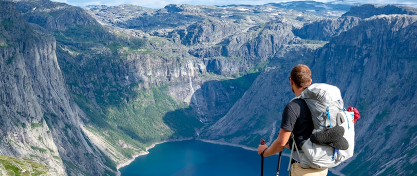 man standing on rock looking towards lake