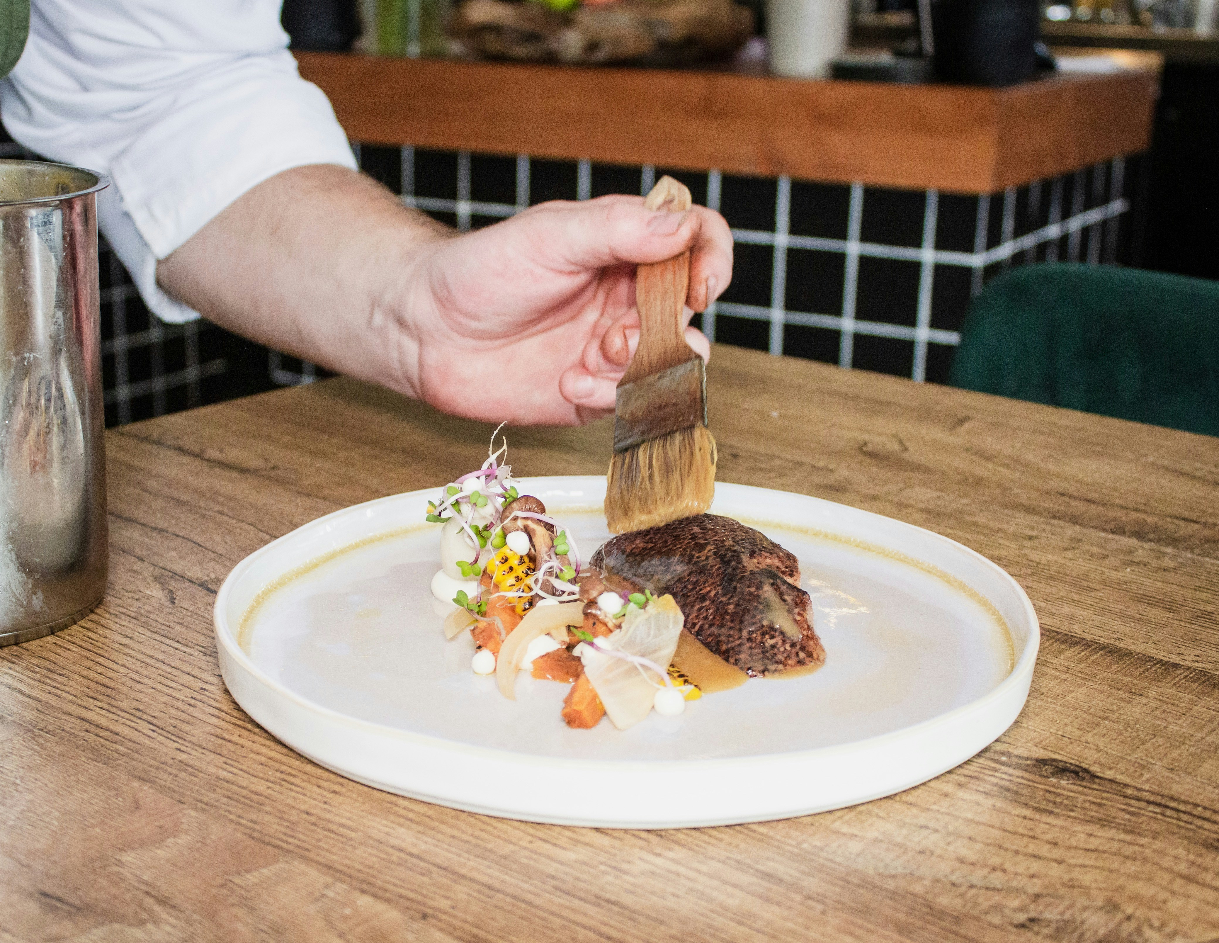 Chef brushing a plated dish