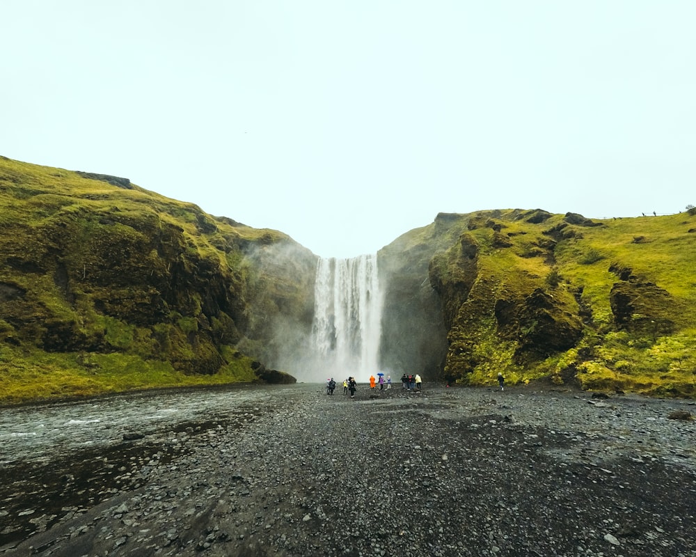 people walking in front of Skogafoss waterfall