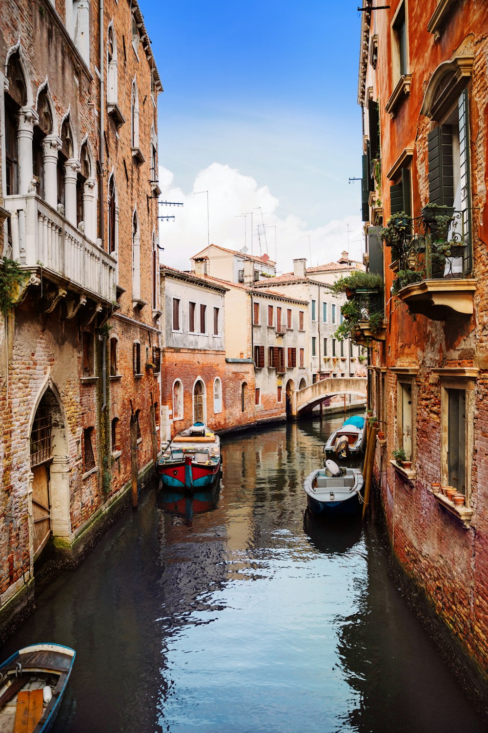 photography of boats near river between buildings during daytime