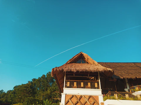 A tropical resort building featuring synthetic thatched roofing under clear blue sky