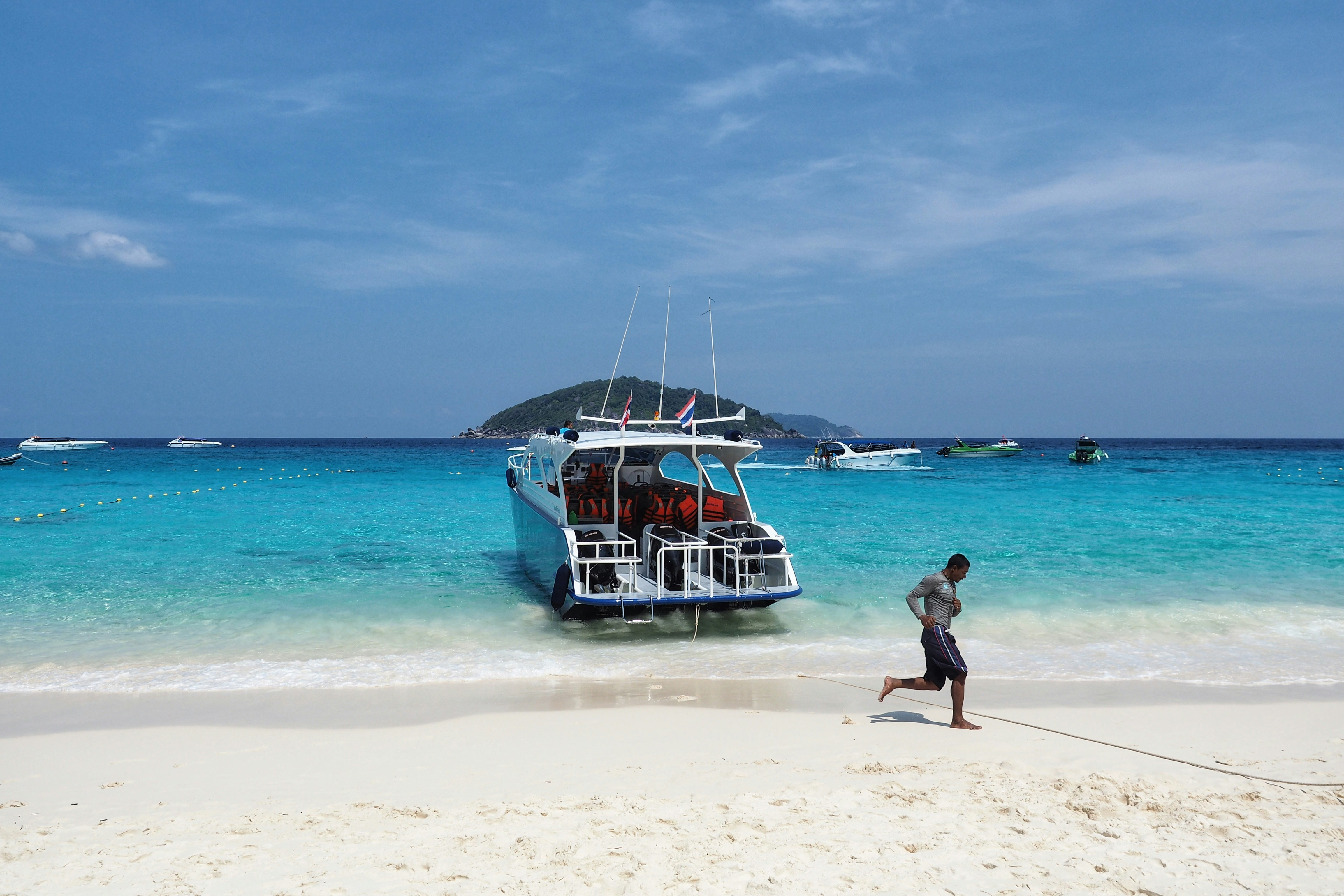 man running on seashore near yacht