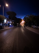 An ujtron street light illuminating a quiet neighborhood road at dusk