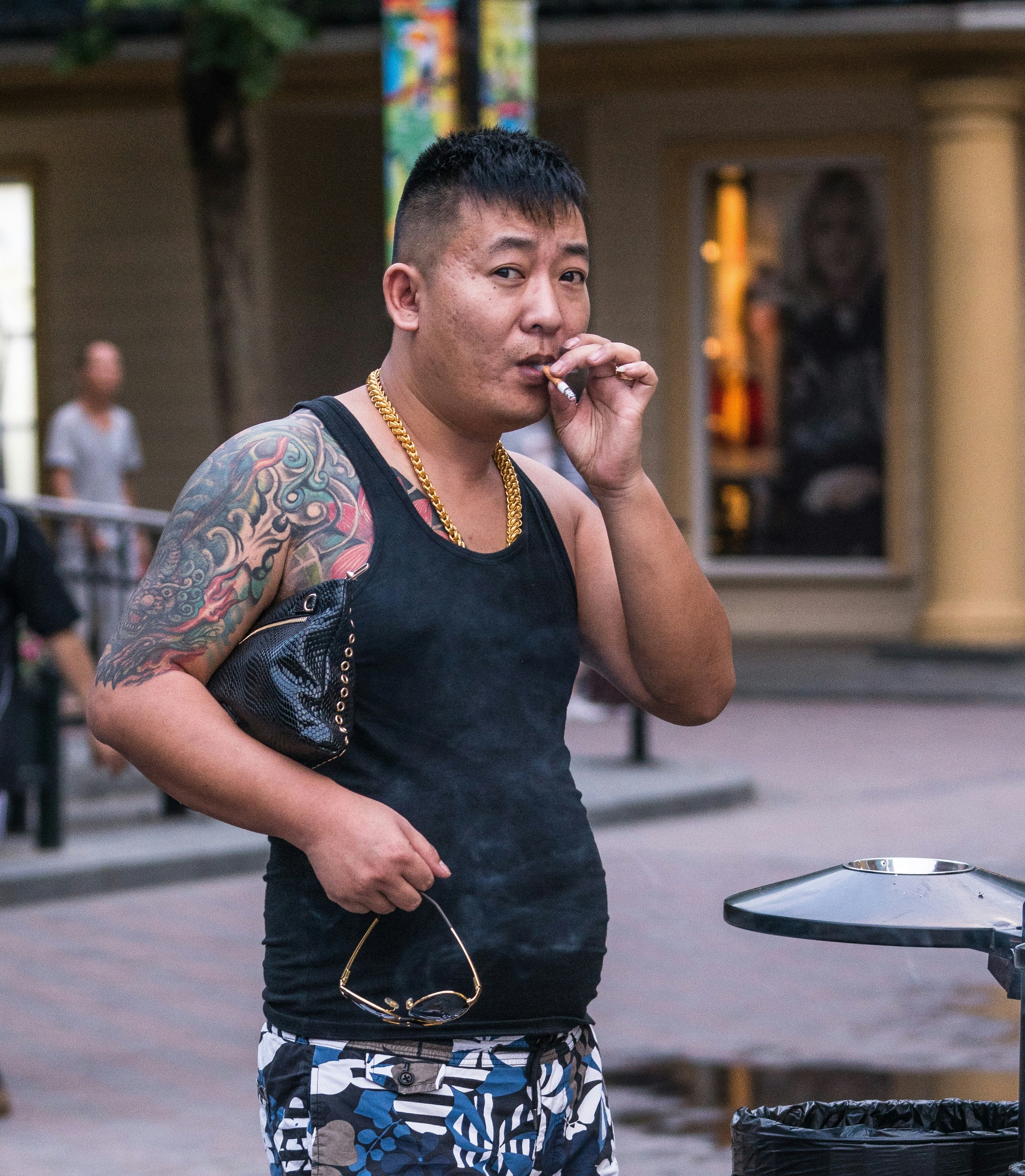 man wearing black tank top smoking while standing