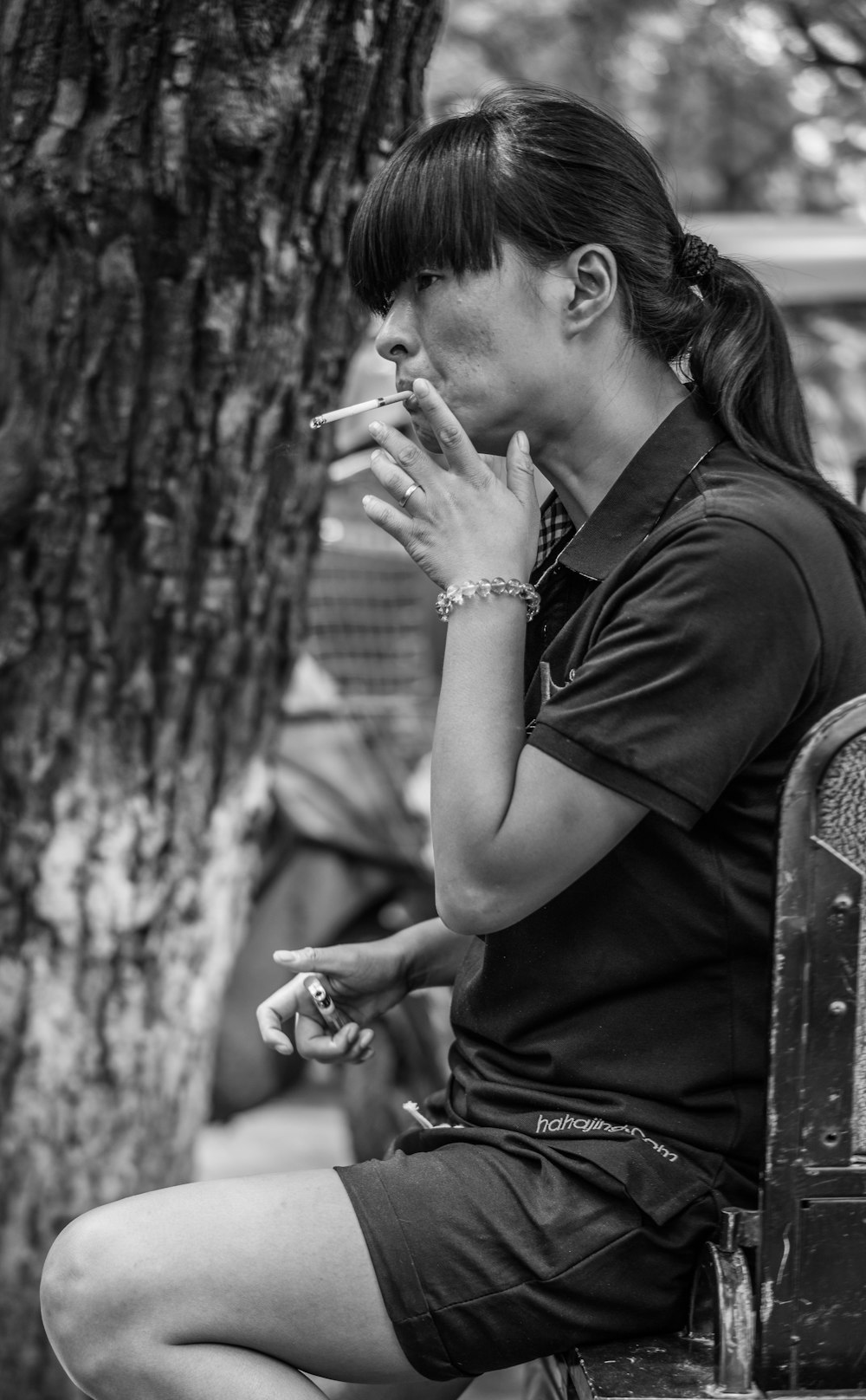 a woman sitting on a bench smoking a cigarette