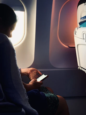 A traveler on the phone looking relieved while viewing a cancelled flight on their laptop screen.