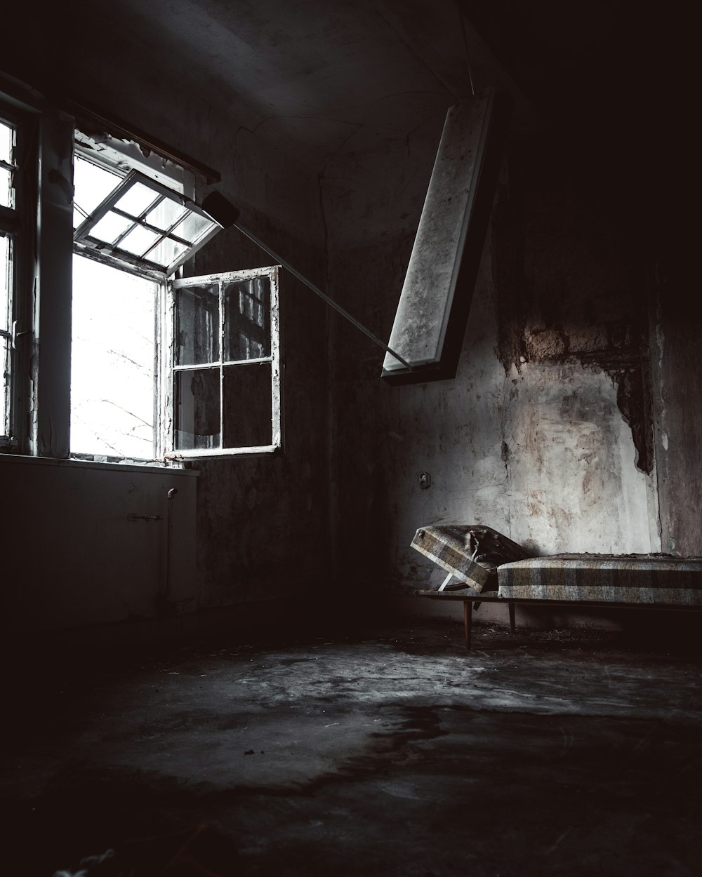 Bett in verlassenem Gebäude in der Nähe des geöffneten Fensters