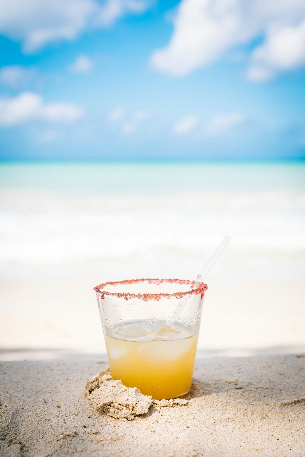 filled clear rock glass in white sand