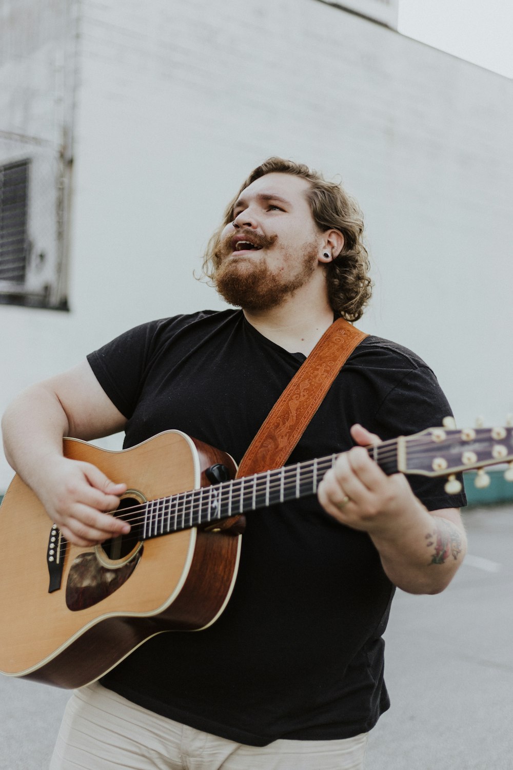 man wearing black shirt playing acoustic guitar