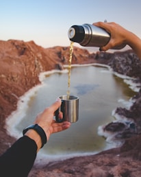 A person enjoying a refreshing drink from a stylish tumbler during an outdoor adventure.