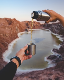 A scenic view with a travel thermos and utensils on a mountain hike.