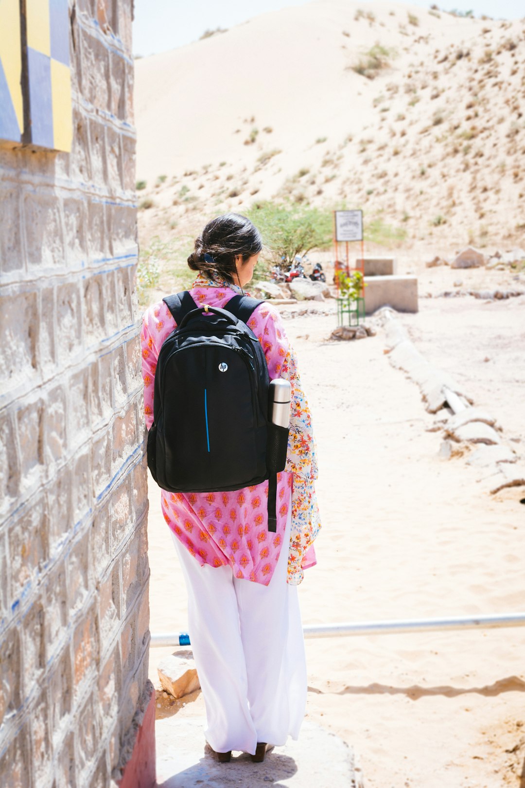 woman carrying backpack leaning on building