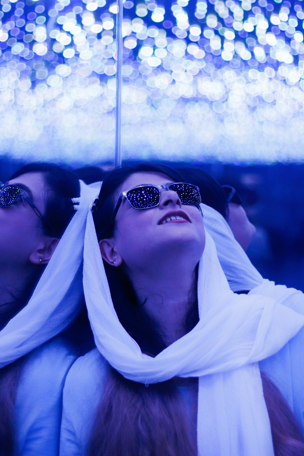 two women wearing sunglasses are under an umbrella