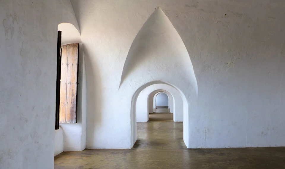 Long, narrow hallway with white walls, arched windows, and curved archway ceiling above