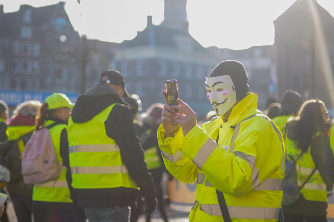 person wearing guy fawkes mask using phone surrounded with people
