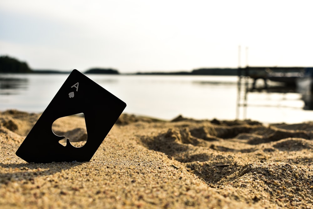 black ace of spades playing card on sand
