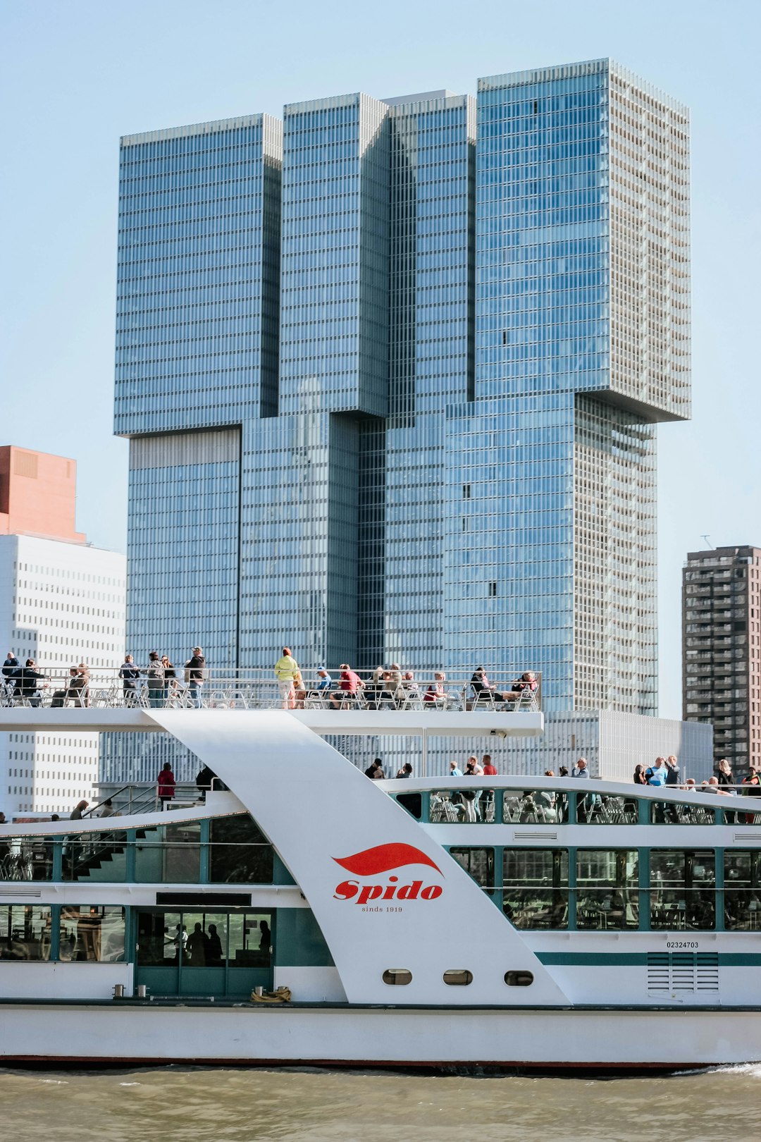 people riding Spide boat near curtain wall high-rise building