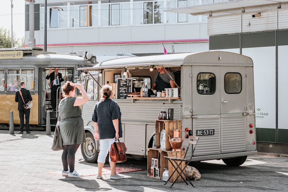 two women standing outside food cart