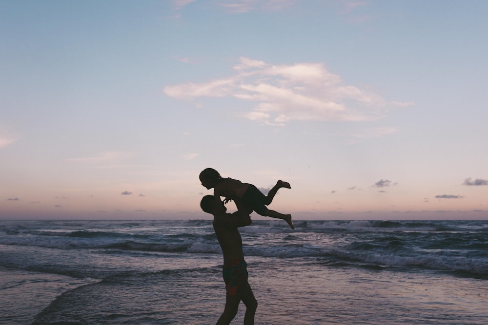 man carrying baby in seashore