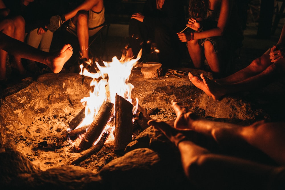 pessoas sentadas perto da fogueira durante a noite