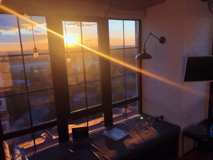 A cozy room with soft lighting, a window showing a twilight sky, and comfortable seating.