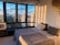 Cozy hotel room with a large window showing a city skyline at sunset.