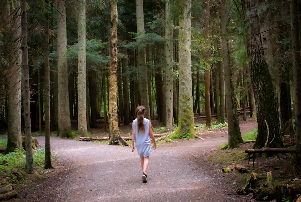 menina que caminha perto de árvores