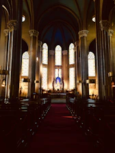 A warm, inviting church interior bathed in soft celestial blue and golden light with people praying together.