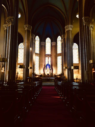 A warm, inviting church interior bathed in soft celestial blue and golden light with people praying together.