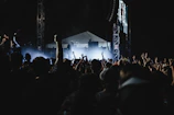 A wide shot of the crowd swaying and cheering as the band plays an outdoor evening concert.